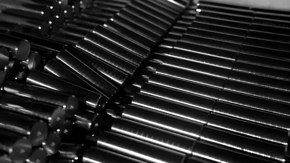 Polished steel bars stacked at the works, a lathe machining a component, and a robot loading parts into a machining centre.